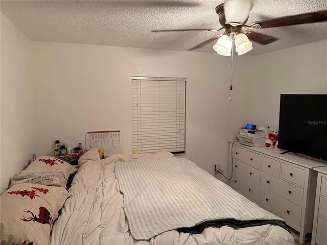 a bedroom with a bed and a flat tv screen on dresser