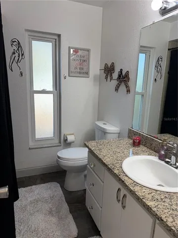 a bathroom with a granite countertop sink toilet and a mirror