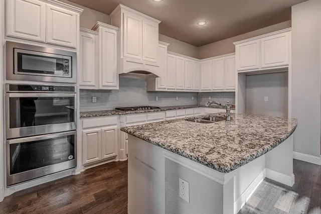 a kitchen with stainless steel appliances granite countertop a sink stove and microwave