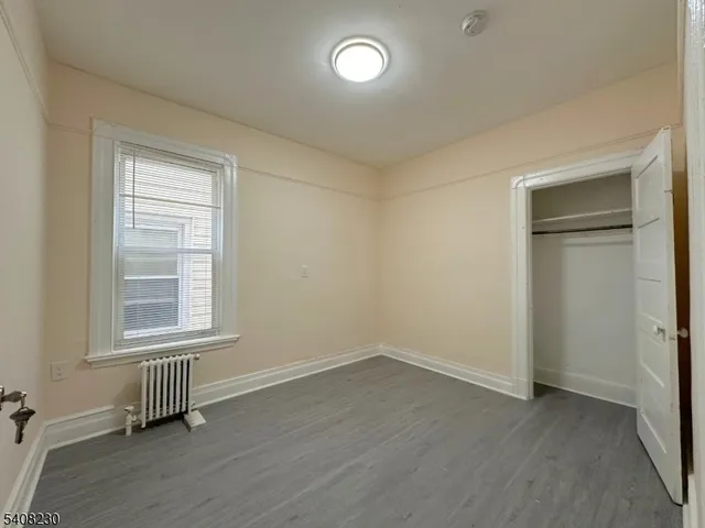 an empty room with wooden floor cabinet and windows