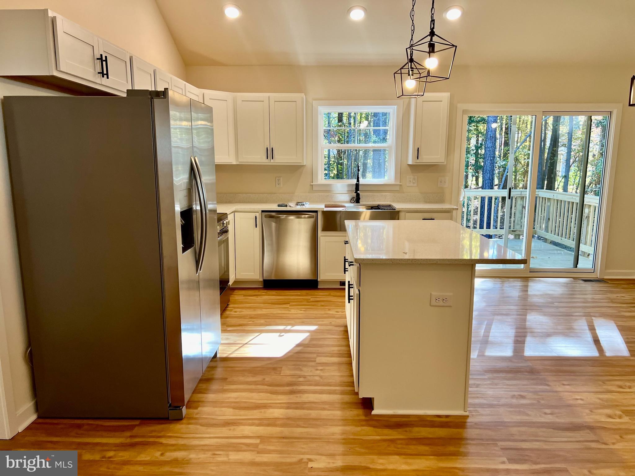 73 Azalea Way Colonial Beach, VA 22443 - Photo 5 of 13 a kitchen with stainless steel appliances granite countertop a refrigerator a sink dishwasher a stove and a dining table with wooden floor