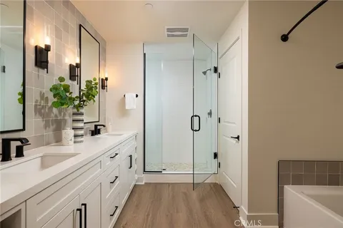 a bathroom with a double vanity sink a large mirror a bathtub and shower