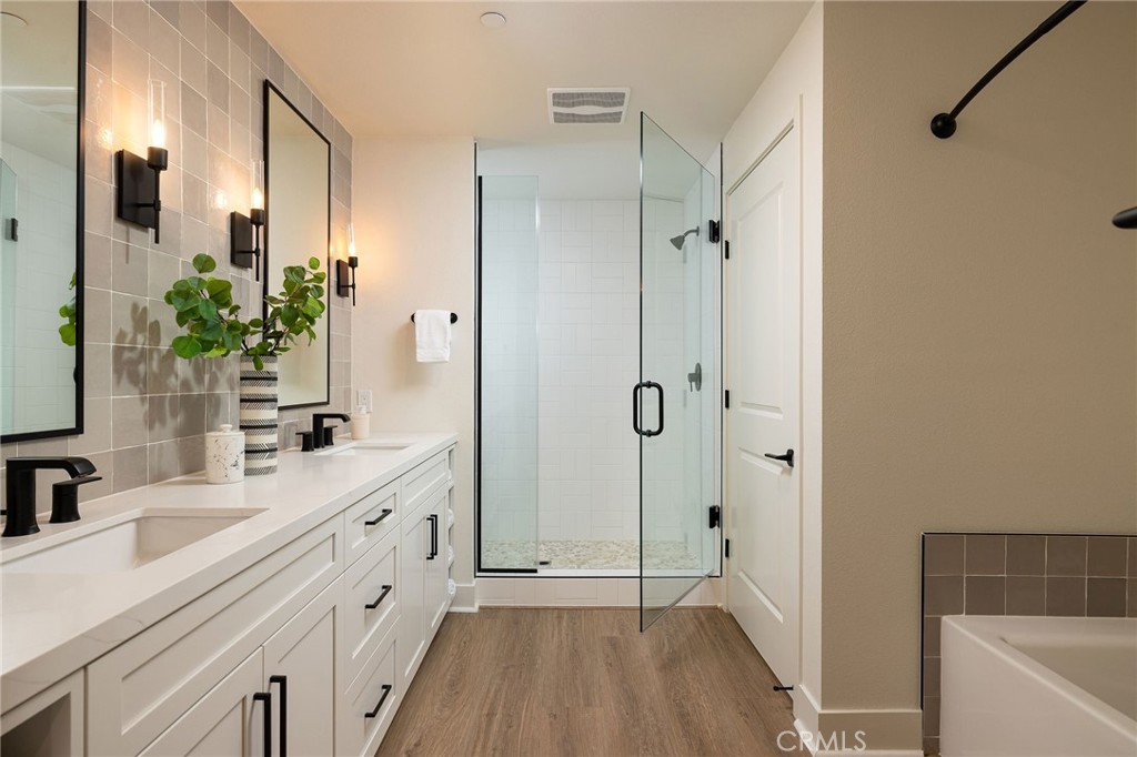 414 Main Street, Unit 410 Huntington Beach, CA 92648 - Photo 14 of 25 a bathroom with a double vanity sink a large mirror a bathtub and shower