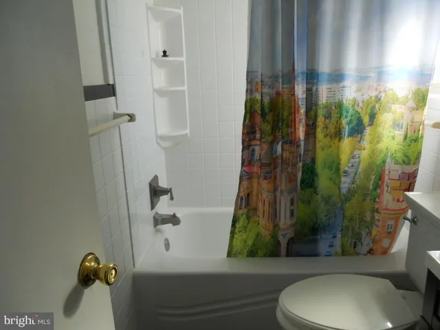 an empty room with a chandelier fan and wooden floor