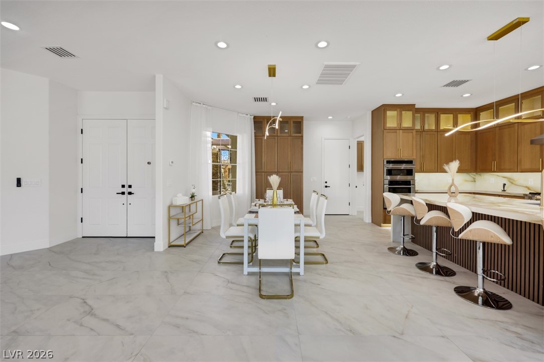 5015 Rivedro Street Las Vegas, NV 89135 - Photo 18 of 91 A sleek, open-concept dining area seamlessly blends with a modern kitchen, featuring a spacious island.