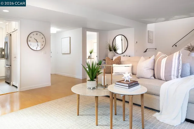 a living room with couches a mirror and a dining table with wooden floor