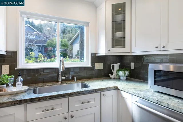 a kitchen with granite countertop a sink a window and cabinets