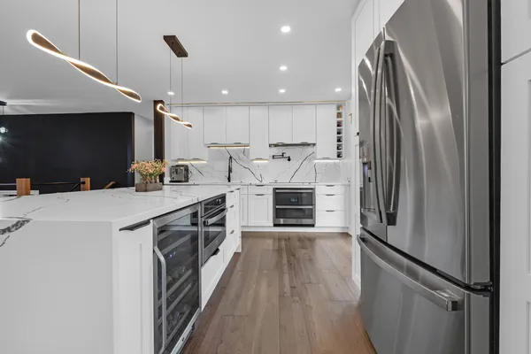 a kitchen with stainless steel appliances a refrigerator sink and wooden floor