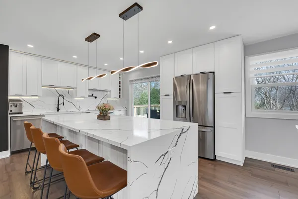 a kitchen with stainless steel appliances granite countertop a table chairs and a refrigerator