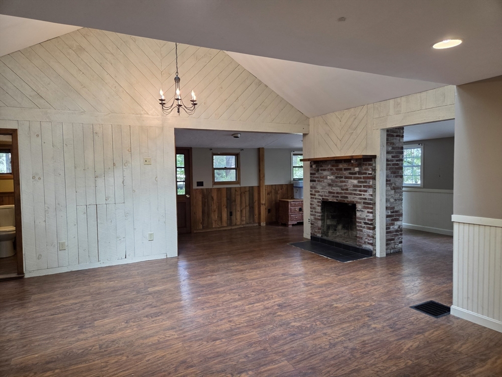 659 Reservoir Road Lunenburg, MA 01462 - Photo 11 of 41 an empty room with wooden floor fireplace and windows