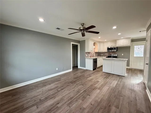 a kitchen with stainless steel appliances kitchen island wooden cabinets and a wooden floor