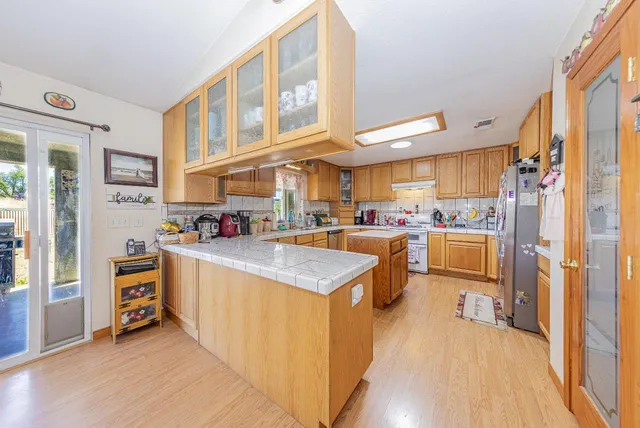 a kitchen with stainless steel appliances granite countertop a refrigerator a stove and a sink with cabinets