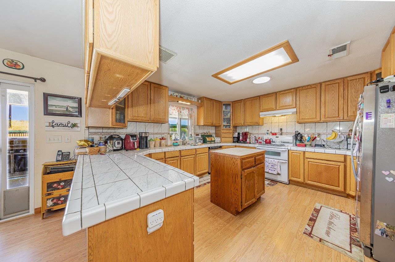 35095 Rough Rider Way Raymond, CA 93653 - Photo 17 of 57 a kitchen with stainless steel appliances granite countertop a sink dishwasher stove and refrigerator with wooden floor