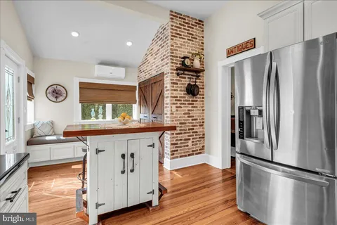 a kitchen with stainless steel appliances a refrigerator a sink a stove a table and chairs