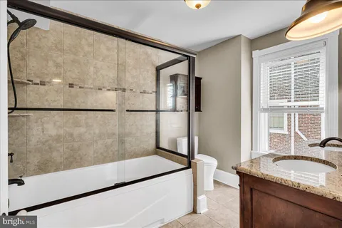 a bathroom with a granite countertop double vanity sink and mirror