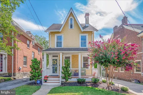 a front view of a house with a garden and trees