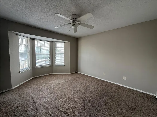 an empty room with a ceiling fan and window