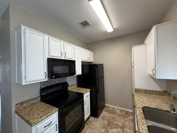 a kitchen with stainless steel appliances granite countertop a stove refrigerator and microwave