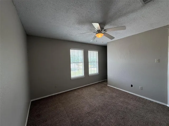 an empty room with windows and ceiling fan
