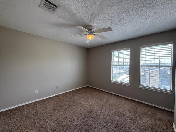 an empty room with chandelier fan and windows