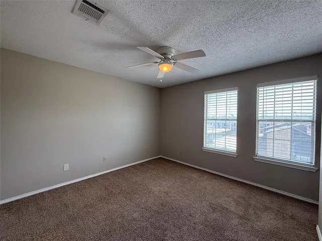 an empty room with chandelier fan and windows