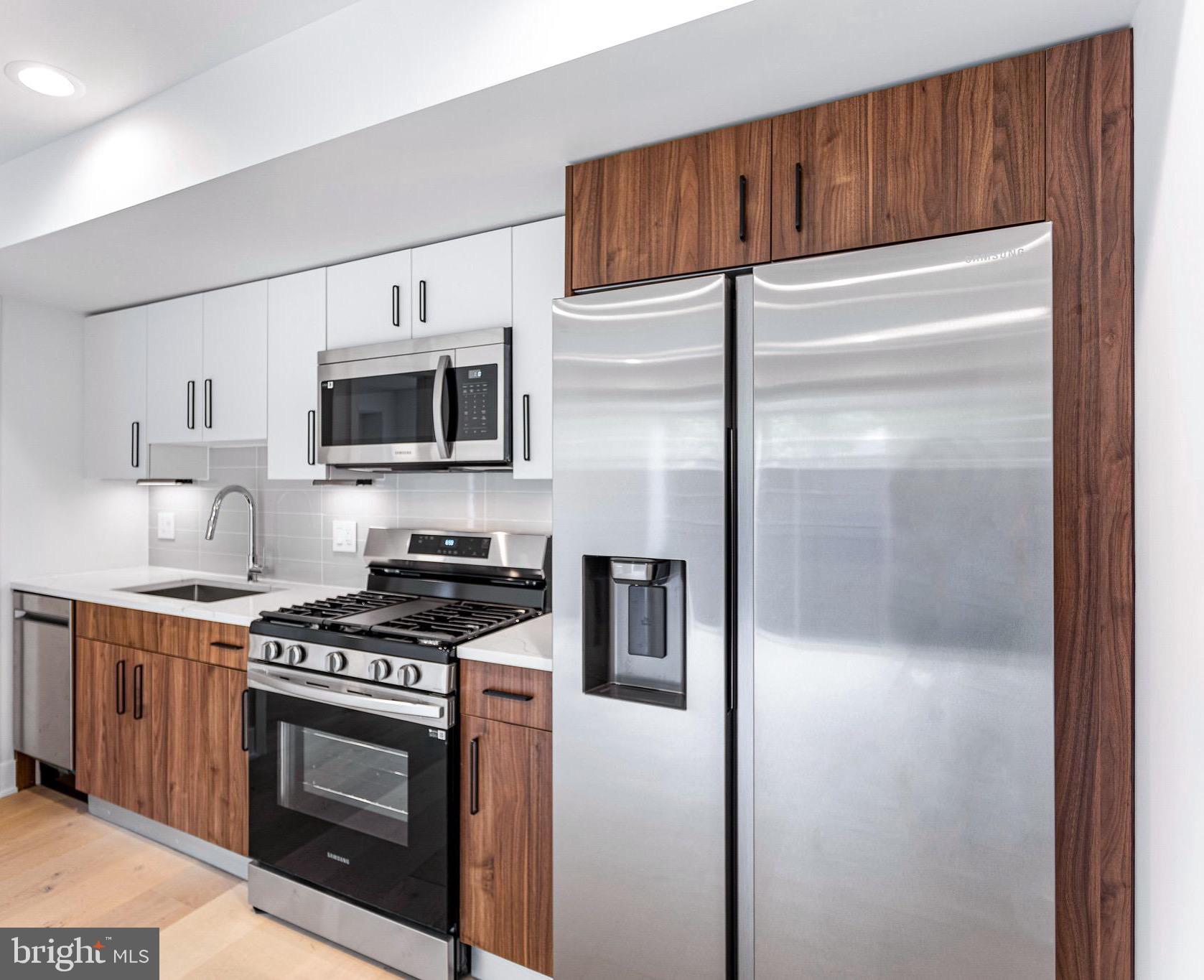 a kitchen with stainless steel appliances granite countertop a refrigerator a stove and a sink with wooden floor