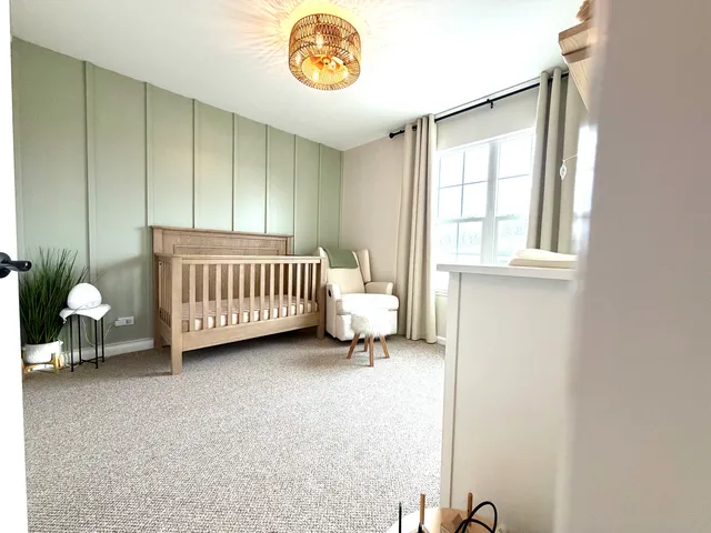 a room with a baby crib and a chair