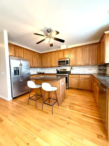 a kitchen with stainless steel appliances kitchen island granite countertop a table chairs sink and cabinets