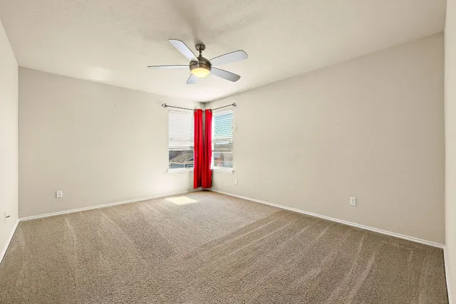 an empty room with a ceiling fan and carpet