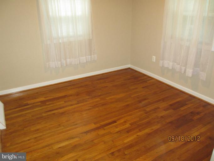 12418 Dewey Road Rockville, MD 20853 - Photo 6 of 20 a view of an empty room with wooden floor and a window