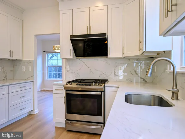 a kitchen with granite countertop a stove a sink and a microwave
