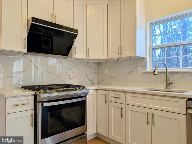 a kitchen with stainless steel appliances granite countertop white cabinets and a stove top oven
