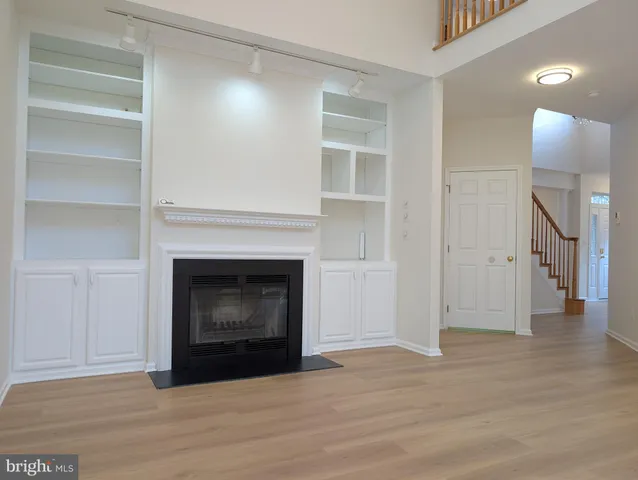 a view of an empty room with wooden floor and a fireplace