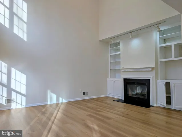 a view of an empty room with wooden floor fireplace and a window