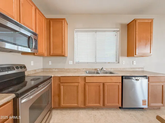 a kitchen with stainless steel appliances granite countertop a refrigerator a sink dishwasher a stove and a refrigerator with wooden floor