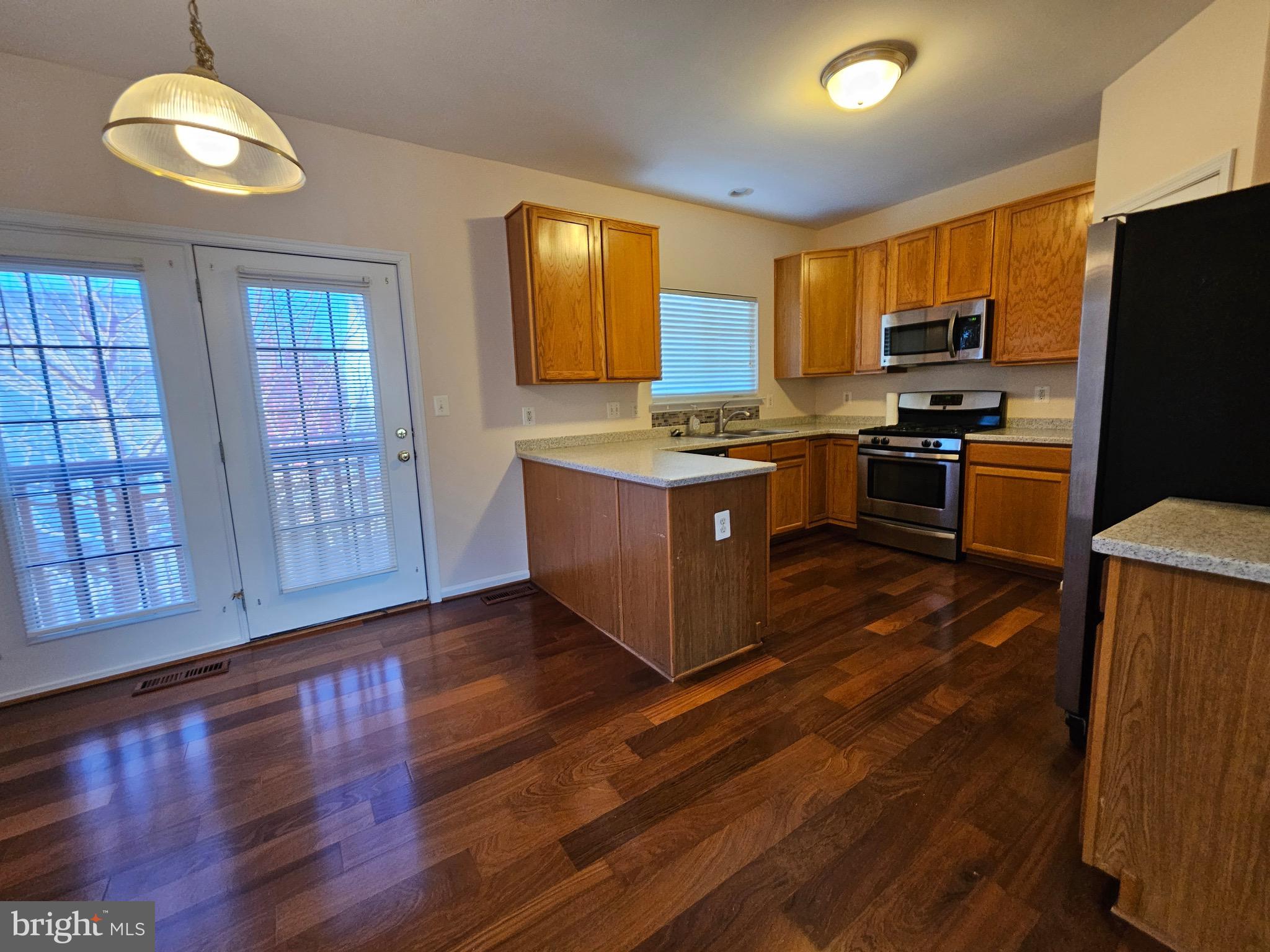 2238 Blue Spruce Drive Culpeper, VA 22701 - Photo 4 of 18 a kitchen with stainless steel appliances granite countertop a stove top oven a refrigerator a kitchen island with wooden floors and cabinets
