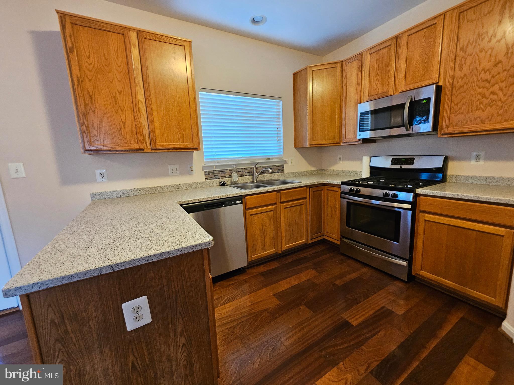 2238 Blue Spruce Drive Culpeper, VA 22701 - Photo 5 of 18 a kitchen with stainless steel appliances granite countertop wooden cabinets a stove a sink and a microwave
