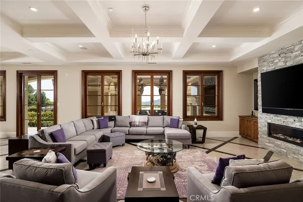 a living room with furniture kitchen view and a chandelier