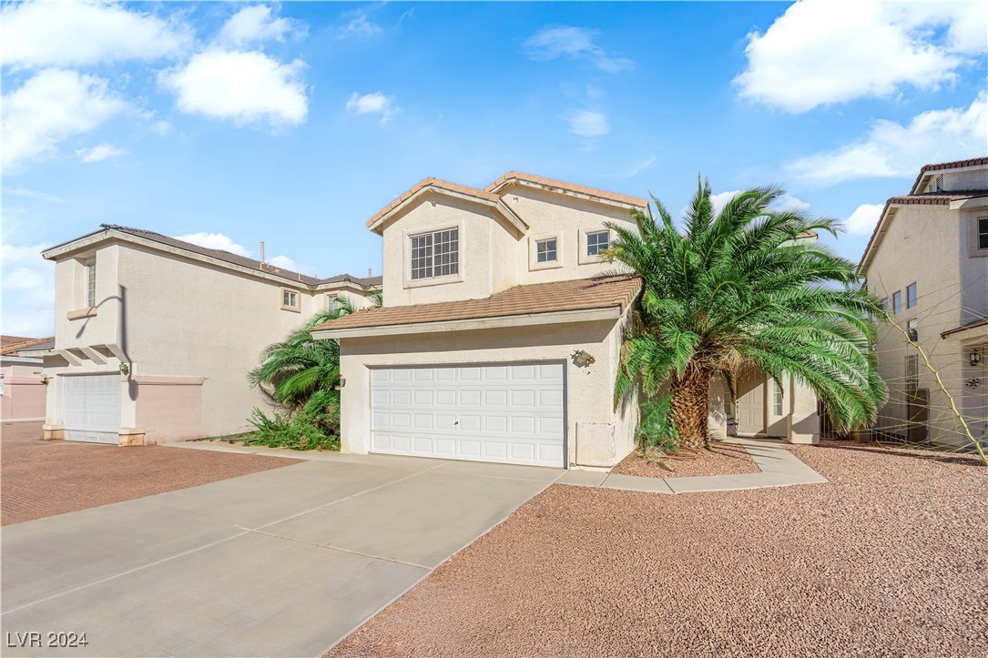 Mediterranean / spanish-style house with a garage, driveway, stucco siding, and a tile roof