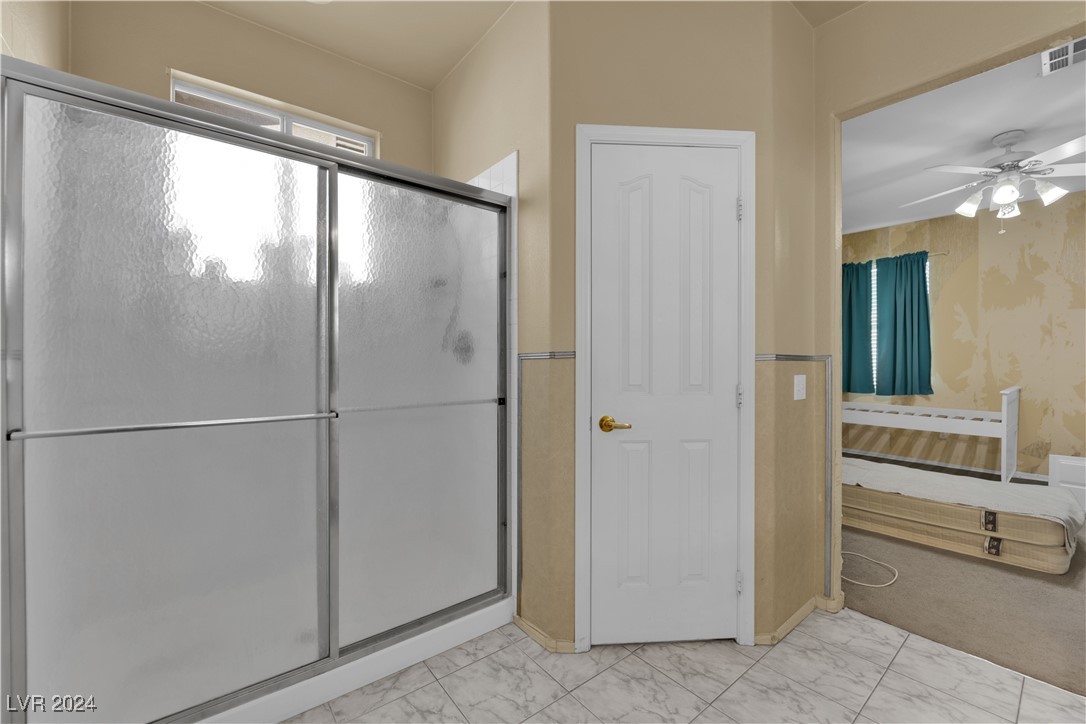 5790 Native Dancer Court Las Vegas, NV 89113 - Photo 19 of 26 Full bath featuring ensuite bath, light marble finish floors, a ceiling fan, and a stall shower
