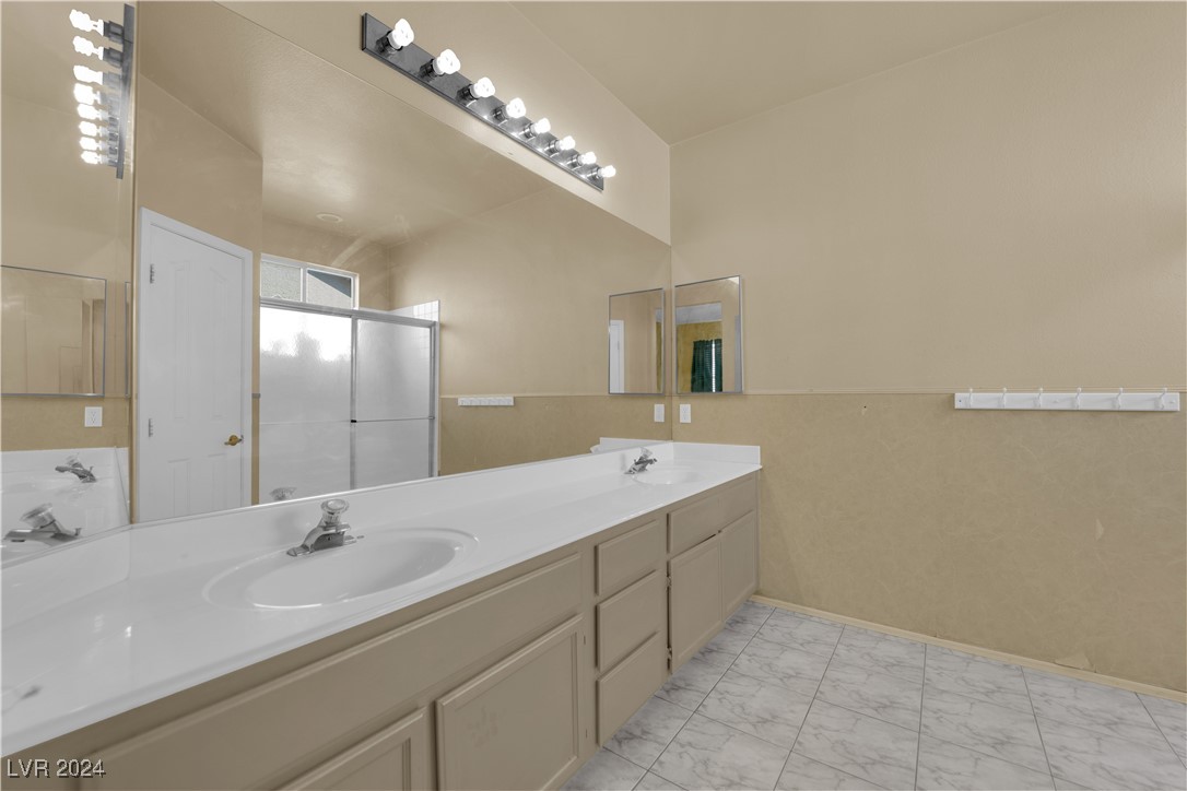 5790 Native Dancer Court Las Vegas, NV 89113 - Photo 20 of 26 Bathroom with double vanity, light marble finish flooring, and a shower stall