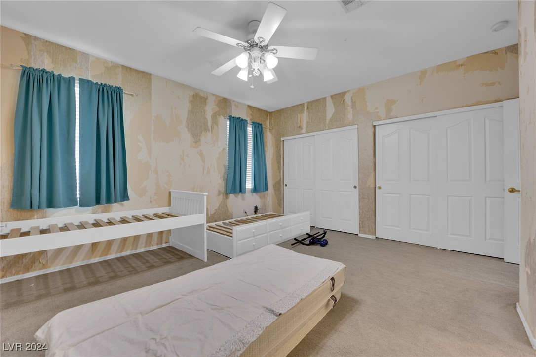 5790 Native Dancer Court Las Vegas, NV 89113 - Photo 21 of 26 Carpeted bedroom with wallpapered walls, a ceiling fan, and multiple closets