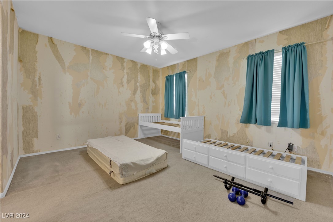 5790 Native Dancer Court Las Vegas, NV 89113 - Photo 22 of 26 Bedroom with wallpapered walls, a ceiling fan, and carpet floors