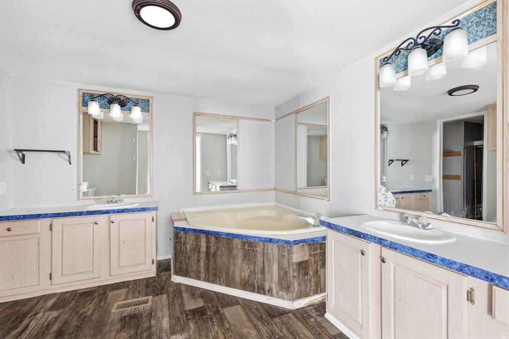316 Summit Drive Springtown, TX 76082 - Photo 13 of 39 The bathroom features a corner soaking tub, two separate vanities with sinks, and light wood cabinetry with blue countertops