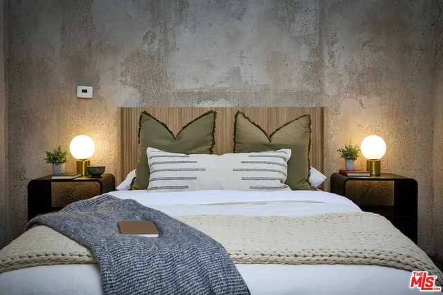 a bedroom with a bed and a lamp on the dresser