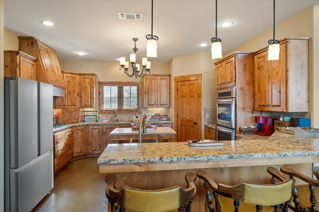 a kitchen with kitchen island granite countertop wooden cabinets and refrigerator