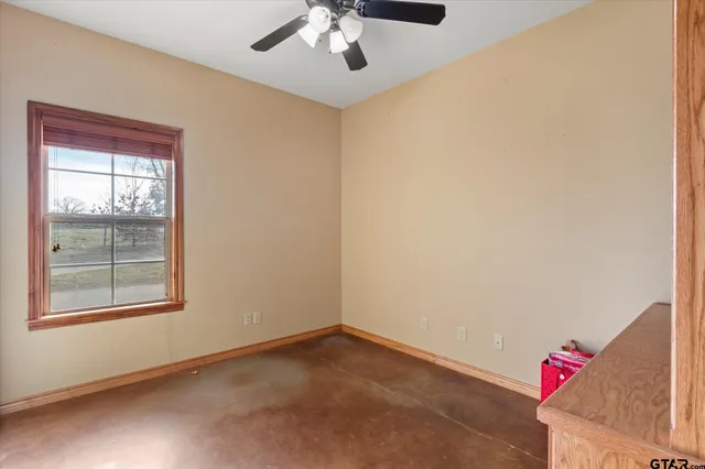 an empty room with a window and ceiling fan