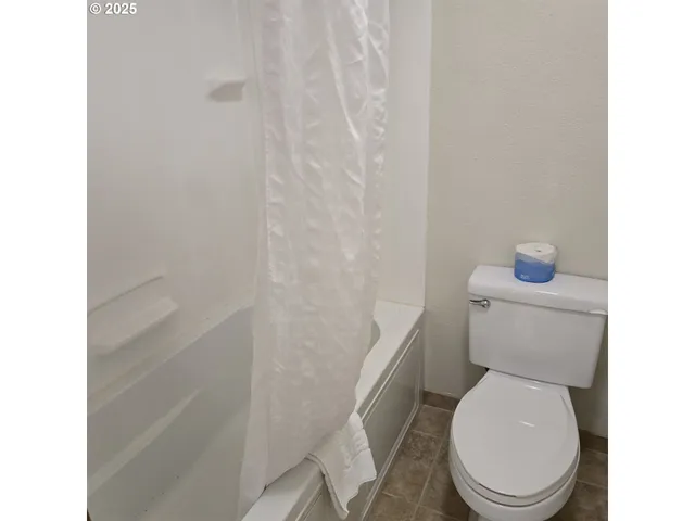 a white toilet sitting next to a shower