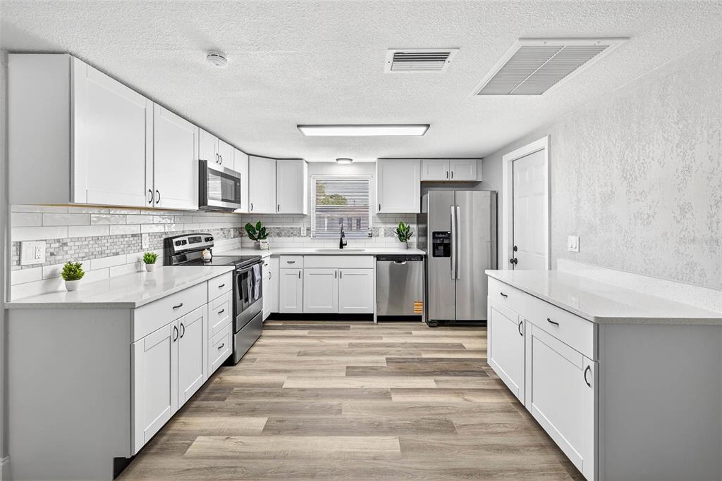 7835 Birchwood Drive Port Richey, FL 34668 - Photo 6 of 14 a kitchen with white cabinets stainless steel appliances and sink