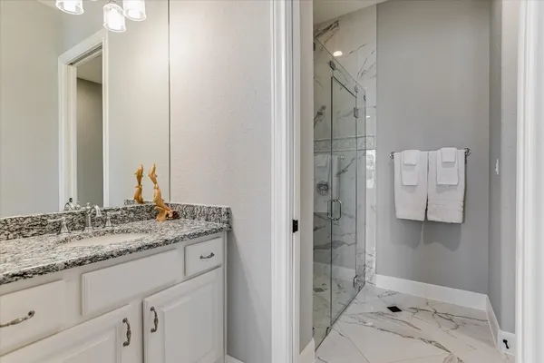 a bathroom with a granite countertop sink a shower and a mirror